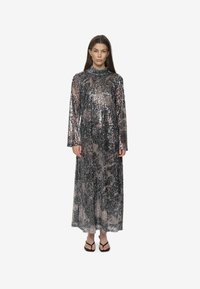 Abito lungo a maniche lunghe realizzato in tessuto di paillettes argento e nero, con un colletto alto e una vestibilità morbida.