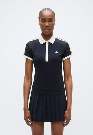 Polo blu navy con colletto e dettagli bianchi, maniche corte e gonna plissettata, realizzato in un tessuto liscio ed elastico.