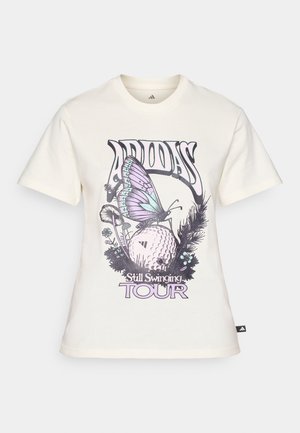 Krämfärgad bomullströja med en grafisk design av en lila fjäril, en golfboll och blommönster samt texten "ADIDAS Still Swinging TOUR".