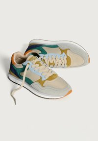 Sneakers beige con accenti verdi, blu e arancioni. Realizzati in suede e mesh, presentano una suola in gomma e chiusura con lacci.