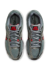 Zapatillas deportivas de malla gris con acentos metálicos plateados y detalles en rojo. Cuentan con una suela acolchada y cordones texturizados. Marca Nike visible.