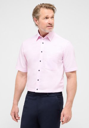 Camicia leggera a maniche corte di colore rosa chiaro con colletto alla francese, dotata di bottoni neri e taschino sul petto. Il materiale sembra liscio e tessuto.