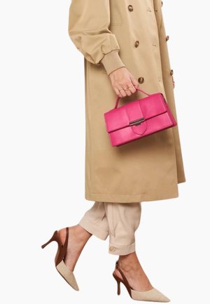 Femme portant un trench-coat beige et un pantalon retroussé, tenant un sac à main rose vif, chaussée de talons slingback beige et marron.