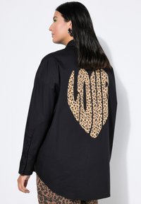 Black button-up shirt featuring a large leopard print "LOVE" graphic on the back. The fabric is smooth with long sleeves and a curved hem.
