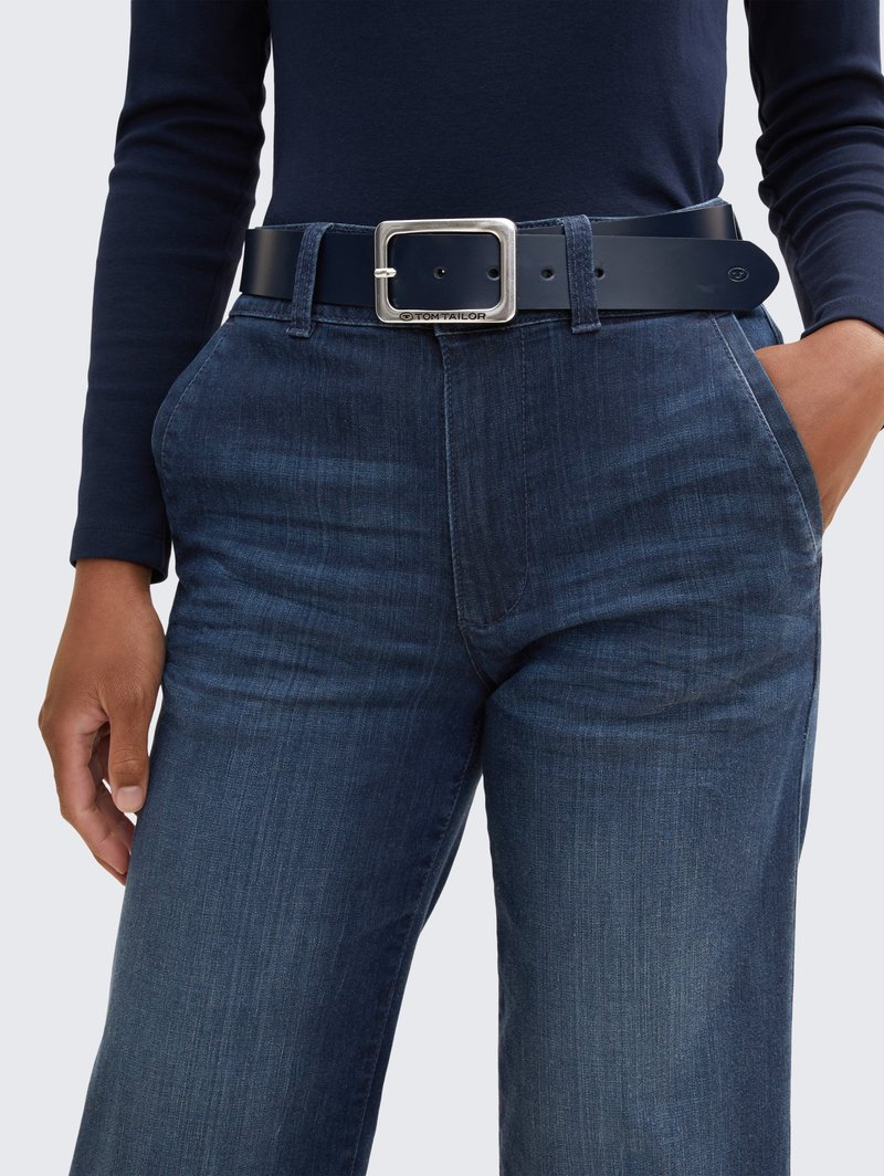 Námornícky dlhý rukáv spárovaný s tmavomodrými denimovými nohavicami. Čierny opasok s obdĺžnikovou striebornou prackou, 2 viditeľné vrecká a štruktúrovaná tkanina.