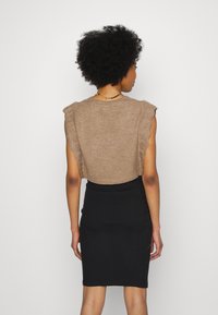 Top crop castanho com detalhes em ondas, combinado com uma saia lápis justa preta e canelada, com foco na textura e design.