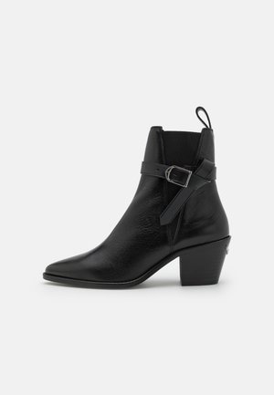 Black leather ankle boot with pointed toe, block heel, and side buckle detail. Features smooth texture and a pull tab at the back.