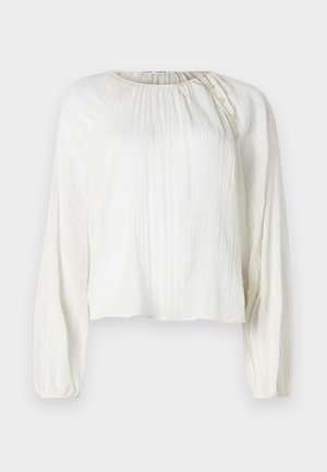 Gaišs, krēmkrāsas blūze ar garām piedurknēm, teksturēta auduma, apaļa dekoltē un pogu detaļa plecā.