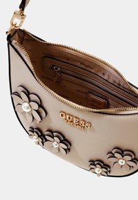 Borsa a spalla in similpelle beige con applicazioni floreali nere e dettagli in perle, hardware dorato e tasca interna con zip.