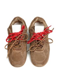 Brązowe zamszowe sneakersy z czerwono-białymi wzorzystymi sznurówkami, okrągłym noskiem i jasnobrązowymi gumowymi podeszwami. Posiadają akcenty przeszyć po bokach.