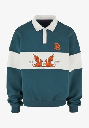 Teel- ja valge värvi pikakä sleeve polo-stiilis särk nuppudega, millel on oranž emblem ja kaks grifi graafikat rinnal.