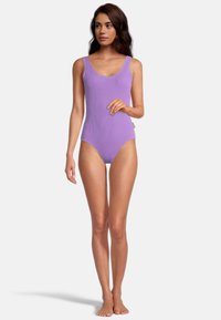 Maillot de bain une pièce violet à côtes avec des bretelles larges et un décolleté arrondi, présentant un dos dégagé et un minimalisme dans le détail des coutures.