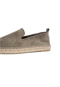 Suede slip-on w szarym odcieniu z plecioną juteową podeszwą i przeszywanym akcentem. Posiada boczny uchwyt ułatwiający zakładanie.