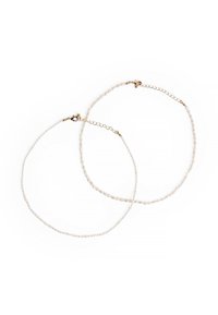 Transparante kraal ketting met kleine, onregelmatige parels en hardware in gouden tint. Voorzien van een karabijnsluiting en een verstelbare ketting voor lengte.