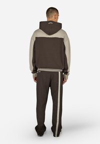 Hætte sweatshirt i mørkebrun og lys grå, med en afslappet pasform, ribbede mansjetter og matchende sweatpants med en sidelinje.