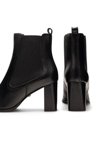 Must musta ankle-kingad elastsete külgpaneelide, ruudukujuliste kandade ja lihtsa selga tõmbamise jaoks mõeldud tõmblukkudega. Sile tekstuur koos õmblustega detailidega.