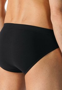 Mutande nere in stile slip con una vita senza cuciture. Il tessuto appare liscio e morbido, progettato per una silhouette aderente.
