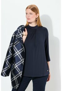 Merikansin paita korkean kaula-aukon ja laskoksilla, yhdistettynä musta-valkoiseen ruutujakkuun. Sujuva kangas, 3/4 hiat ja rento leikkaus.