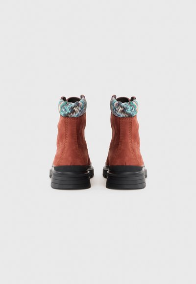 Brown suede ankle boots with a patterned multi-color collar and black rubber soles, featuring stitched details for added texture.