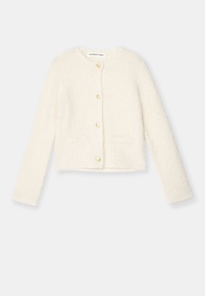 Un cardigan blanc en peluche avec des manches longues, des boutons dorés et deux poches avant. Texture douce et design court.