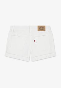 Shorts en denim blanc avec un ourlet replié, deux poches arrière et un patch de marque en cuir marron sur la ceinture.