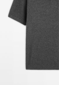 Pull en maille à manches courtes gris charbon avec tissu texturé et ourlet côtelé sur fond blanc.