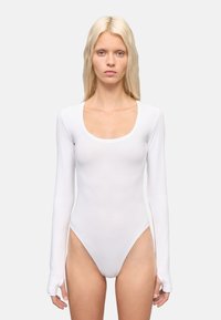 Body de manga larga blanco con escote en forma de U, hecho de un tejido liso y elástico. Presenta un diseño ajustado y aberturas de pierna de corte alto.