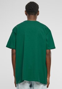 Grøn bomulds t-shirt med løs pasform, korte ærmer og klassisk rund hals. Bagsiden er glat med en lige forneden.