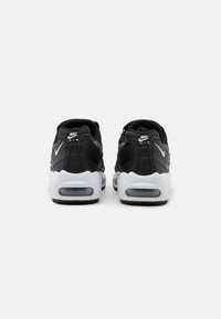 Black and white Nike Air shoes with a chunky sole, textured leather upper, visible air cushioning, and logo on the heel.