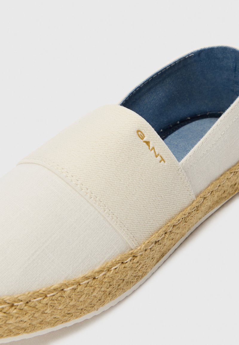 Vit canvas espadrillo med jutesula, med en guldig logotypaccent på den övre remmen och en mjuk denimfoder inuti.