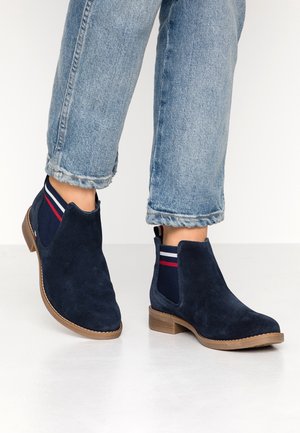 Stivaletti alla caviglia in suede blu navy con pannelli laterali elasticizzati decorati da righe rosse e bianche; suola color marrone chiaro; punta arrotondata; design casual.