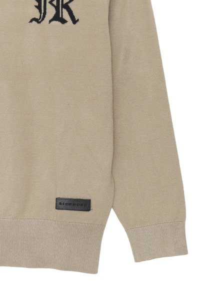 Maglione lavorato a maglia beige con un logo nero prominente sul petto e una patch in pelle nera con la scritta "RICHMOND" sull'orlo.