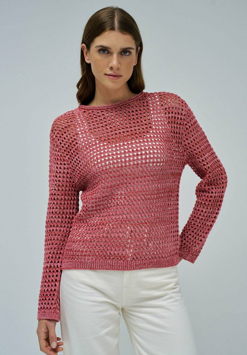 Strickpullover in Pink mit einem lockeren, offenen Strickmuster. Verfügt über lange Ärmel und einen runden Ausschnitt. Kombiniert mit weißen Hosen.