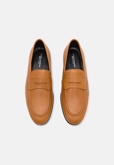 Tan leather loafers with a penny slot design, rounded toe, and contrasting black sole. Smooth texture with stitched accents.