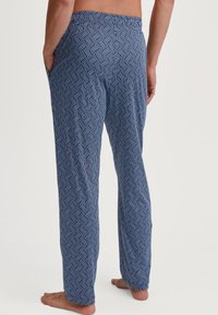 Navy blauwe loungebroeken met een geometrisch wit patroon, voorzien van een elastische tailleband en zijzakken. Zachte stof met een ontspannen pasvorm.