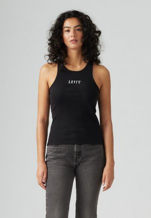Svart ribbestrikket tank topp med rund hals og hvit "LEVI'S"-logo på brystet, sammen med grå høyt liv jeans.