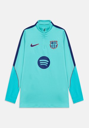 Jasnoniebieska długorękawowa koszulka treningowa FC Barcelona z granatowymi i czerwonymi pasami, logo Nike, herbem klubu oraz logo sponsora Spotify z przodu.