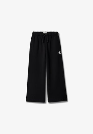 Zwarte broek met wijde pijpen, elastische tailleband en trekkoord, met een klein wit "cK"-logo op de rechterdij.