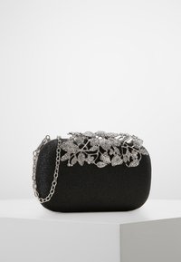 Svart kuvertväska med silverfärgade blommor av rhinestones och en silverkedjesläp, placerad på en vit yta.