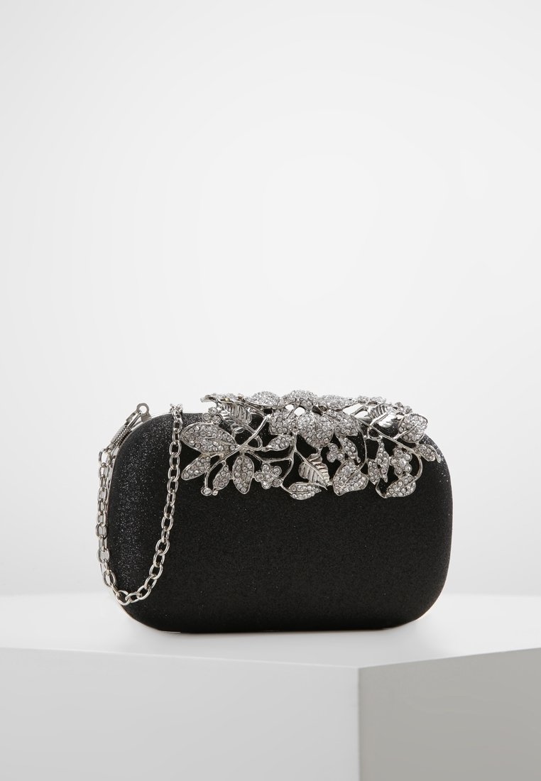 Svart kuvertväska med silverfärgade blommor av rhinestones och en silverkedjesläp, placerad på en vit yta.