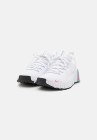 Zapatillas deportivas blancas con parte superior texturizada, suela negra y acentos en rosa y azul. Cuentan con cordones y soporte acolchado.