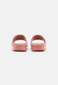Sandali di gomma rosa con apertura sul retro, superficie liscia e bordi arrotondati, dotati di un design ergonomico e suola texturizzata.