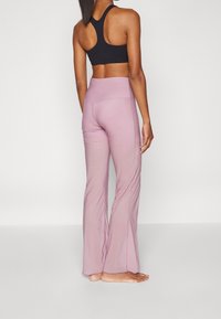 Sujetador deportivo negro de espalda nadadora con pantalones de yoga rosa de vuelo. La tela es suave y los pantalones cuentan con una cintura alta y costuras sutiles.
