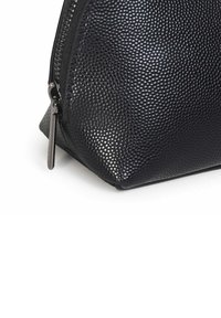 Zwarte, gestructureerde synthetische materialen tas met een ritssluiting, voorzien van een driehoekige vorm en een subtiel geperforeerd ontwerp.