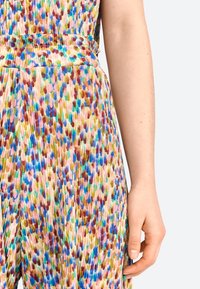 Abito plissettato colorato con un motivo multicolore in verde, blu, rosa e marrone. La vita è accentuata da un dettaglio di cintura sottile.