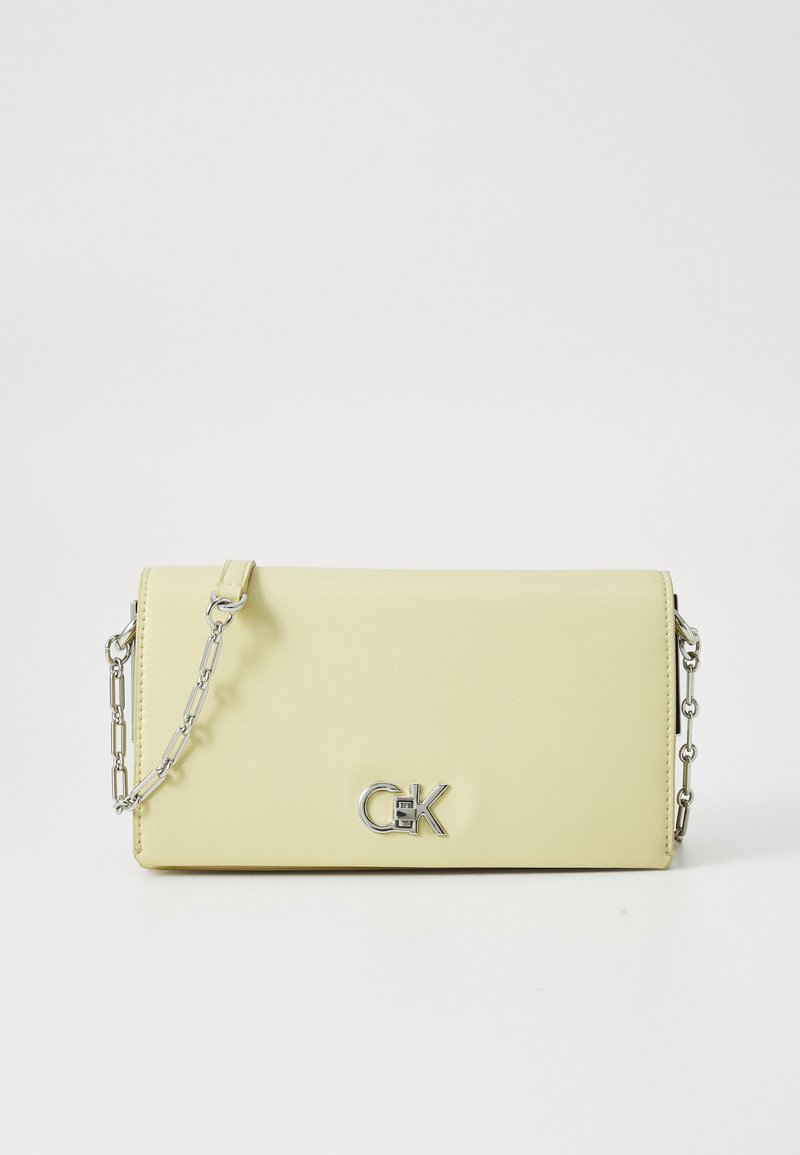 Yellow leather handbag with a smooth texture, featuring a silver chain strap and a metallic logo accent on the front.