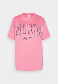 Rosa bomullströja med en stor svart Nike-logotyp över bröstet och en liten Nike-swoosh. Korta ärmar och rundad halsringning.