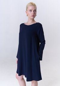 Marineblaues langärmliges Kleid mit weitem Ausschnitt, aus glattem Stoff gefertigt, mit lockerem Schnitt und abgerundetem Saum.