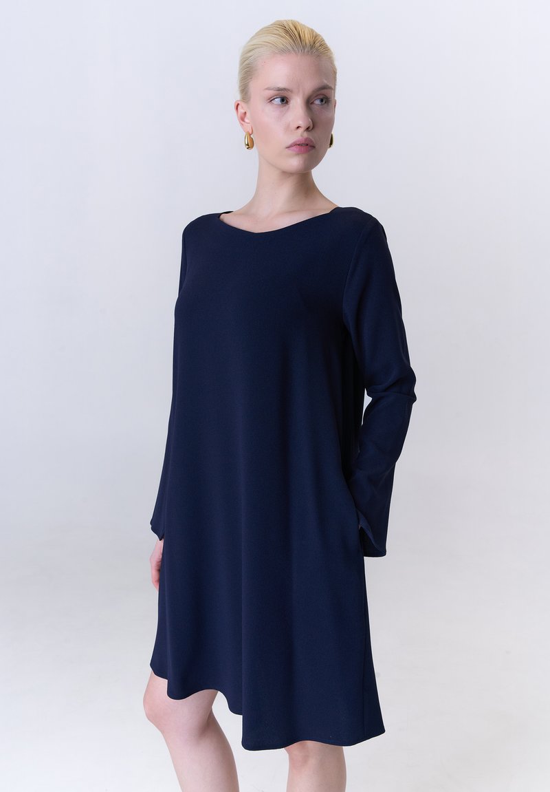 Marineblaues langärmliges Kleid mit weitem Ausschnitt, aus glattem Stoff gefertigt, mit lockerem Schnitt und abgerundetem Saum.