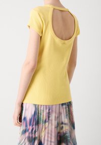 Žluté proužkované tričko s kulatým otevřeným zadním designem, krátké rukávy, s hladkým povrchem, spojené s barevnou plisovanou sukní.